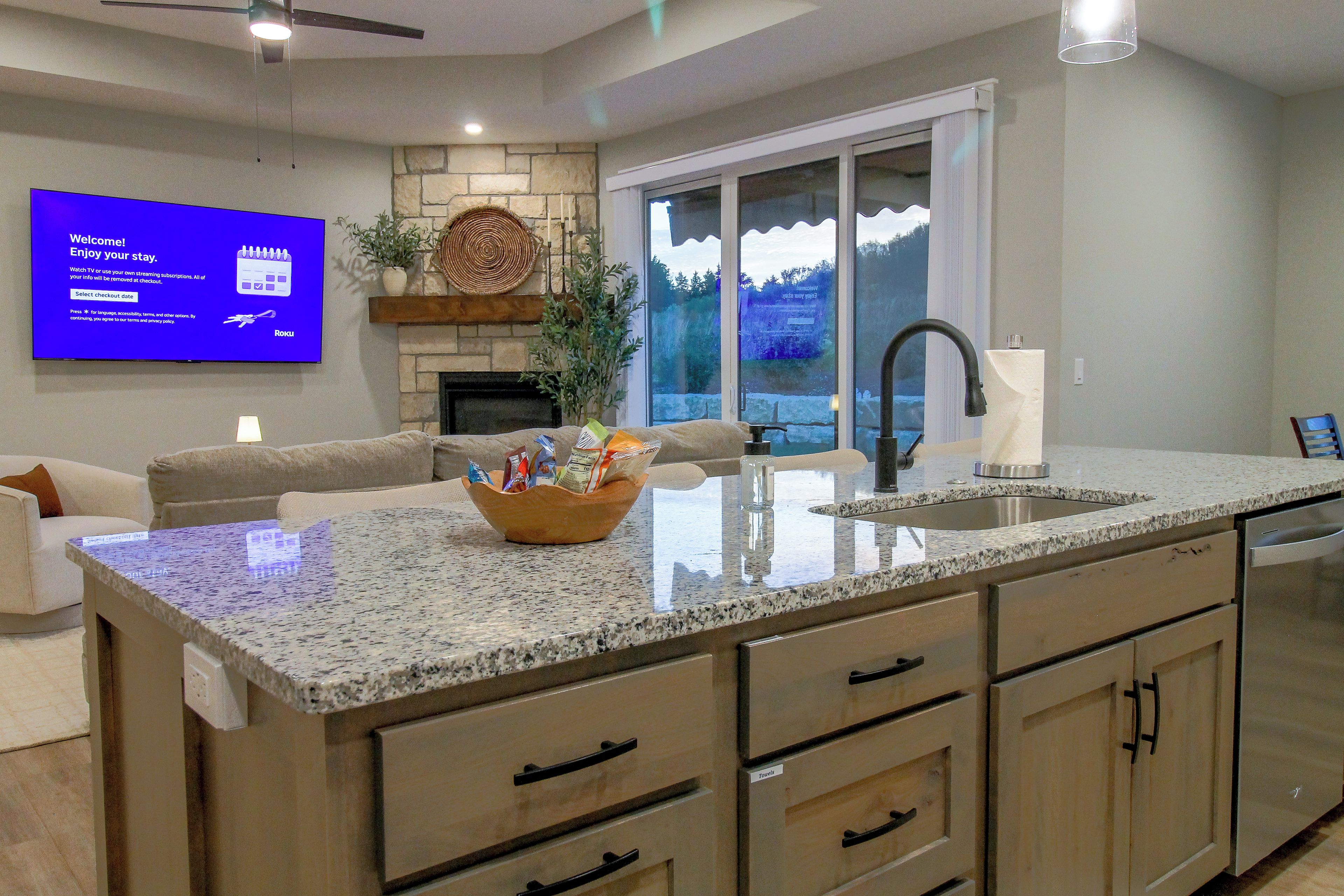 A modern kitchen with granite countertops, a built-in dishwasher, and a large island with a sink.