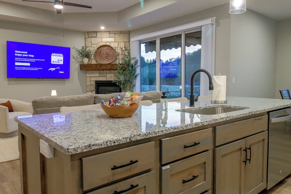 A modern kitchen with granite countertops, a built-in dishwasher, and a large island with a sink.