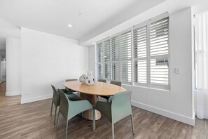 A modern dining area with a round wooden table, six chairs, and decorative vases. - The Esplanade, Palm Beach (Palm Beach)