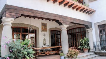 Un edificio tradicional con un patio cubierto, columnas y plantas en macetas.