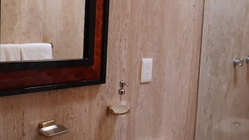 Une salle de bain avec un lavabo en marbre, un miroir, des toilettes et une cabine de douche en verre.