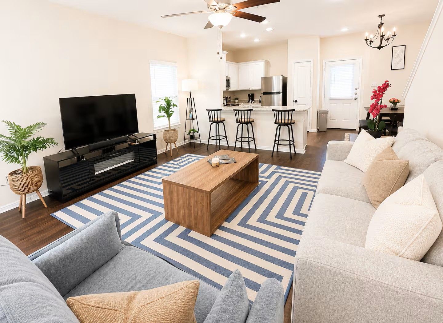 A modern living room with a flat-screen TV, a wooden coffee table, and a grey sofa.