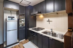 A compact kitchen with dark cabinetry, a built-in microwave, a gas stove, and a stainless steel sink.