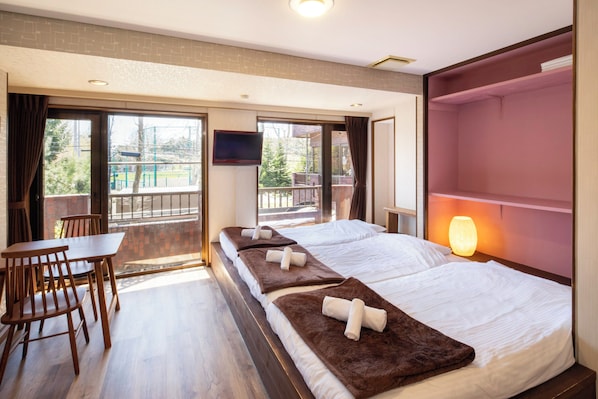 A hotel room with a bed, a desk, a chair, a TV, and a balcony.
