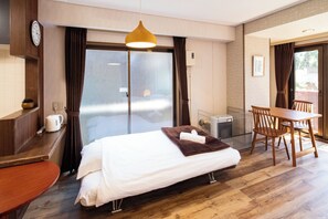 A hotel room with a bed, a desk, a chair, a table, a clock, and a window with curtains. - Sunny Parkside Studio with Park View in Sapporo, Subway 5 min (Sapporo)