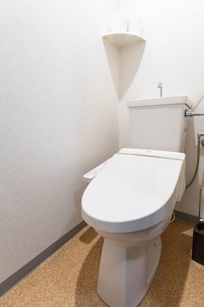 A standard white toilet with a control panel, a wall-mounted flush tank, and a visible pipe. - Sunny Parkside Studio with Park View in Sapporo, Subway 5 min (Sapporo)