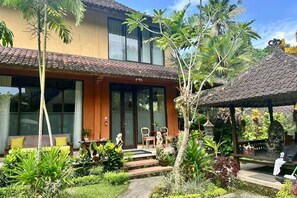 A two-story house with a patio area, outdoor seating, and a garden with tropical plants. - Luxury Villa Near Ubud with Private Gym & Copper Bathtub_PARVATI (Kecamatan Ubud)