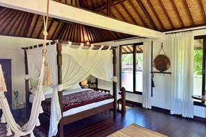 A four-poster bed with a canopy, a hanging macrame chair, and a view of greenery outside. - Luxury Villa Near Ubud with Private Gym & Copper Bathtub_PARVATI (Kecamatan Ubud)