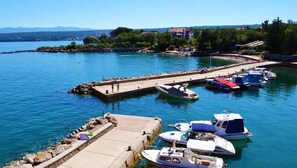 Ein Yachthafen mit vertäuten Booten, eine Pier, die sich ins Wasser erstreckt, und Gebäude im Hintergrund.