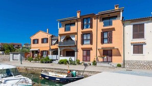 A waterfront property with a dock, a boat, and a building with multiple balconies and windows. - Holiday Apartment My Adria A3 (Vantačići)