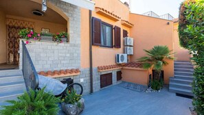 A residential building with a tiled roof, a balcony with flowers, and a staircase leading to the upper floor. - Holiday Apartment My Adria A3 (Vantačići)