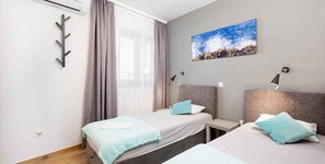 A hotel room with two beds, a window with curtains, a wall-mounted artwork, and bedside lamps. - Holiday Apartment My Adria A3 (Vantačići)