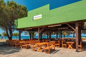 An outdoor seating area with wooden tables and benches, a green awning, and a sign that reads 'Buffet GolN Green.' - Mobile home with air conditioning, terrace and pool (Umag)