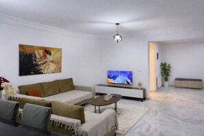 A modern living room with a sofa, coffee table, TV, and artwork. - Appartement Hannibal (Tunis)