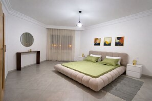 A bedroom with a bed, bedside tables, a mirror, and artwork on the wall. - Appartement Hannibal (Tunis)
