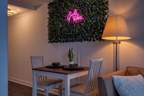 A dining area with a table, chairs, a neon sign, a lamp, and a plant. - Scarborough Skyline Retreat | 2Bed & Balcony (Toronto)