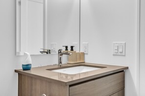 A bathroom with a white sink, a mirror, and a wooden vanity. - Scarborough Skyline Retreat | 2Bed & Balcony (Toronto)
