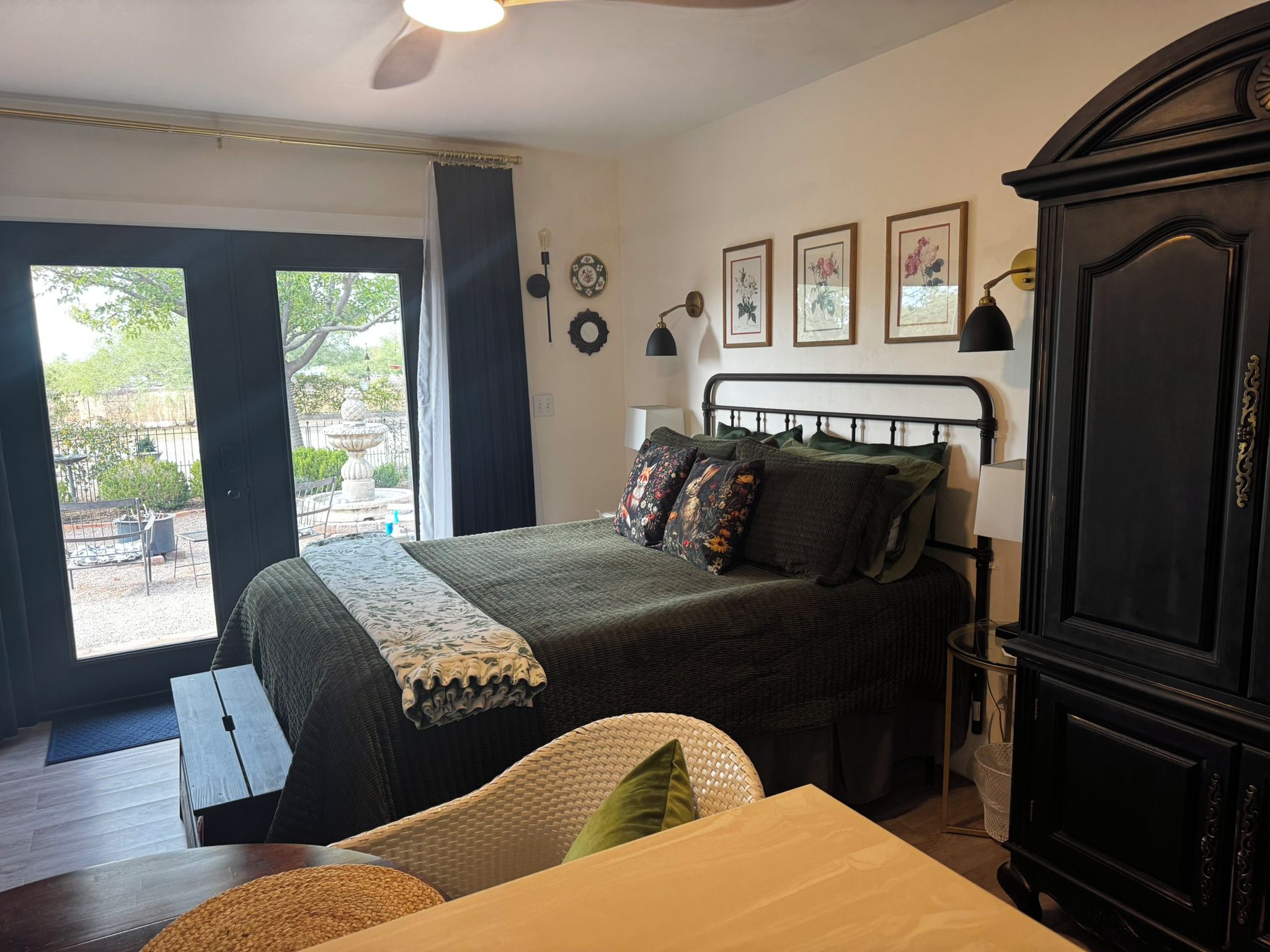 A bedroom with a bed, a desk, a wardrobe, and a view of the outdoors.