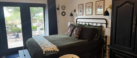 A bedroom with a bed, a desk, a wardrobe, and a view of the outdoors.