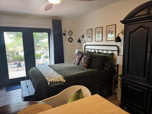 A bedroom with a bed, a desk, a wardrobe, and a view of the outdoors. - Modern Vintage Guest Suite w/ Private Courtyard & Spa Bath (Sierra Vista)