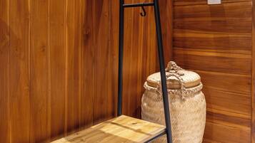 A wooden bench with a metal frame, a woven basket, and a large woven pot against a wooden wall.