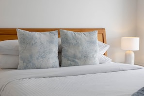 A neatly made bed with a white comforter and two pillows with a tree branch pattern. - Oceanic Beach House | Private Pool | Steps to Sand (Sunshine Coast)