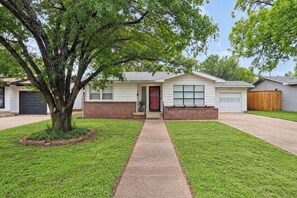 A single-story house with a front entrance, a garage, and a large tree in the front yard. - Ginger Sol - 2BR/1BA - Centrally Located (Lubbock)