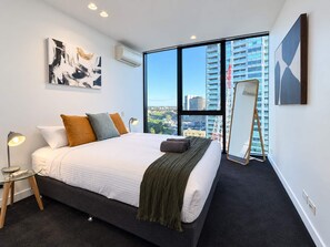 A modern hotel room with a large bed, a standing mirror, and a view of the cityscape through large windows. - Southbank Stunner with 2 Carparks and Dream Views (South Melbourne)