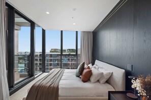 Une chambre moderne avec un grand lit, une vue sur la ville et un mur de couleur sombre.