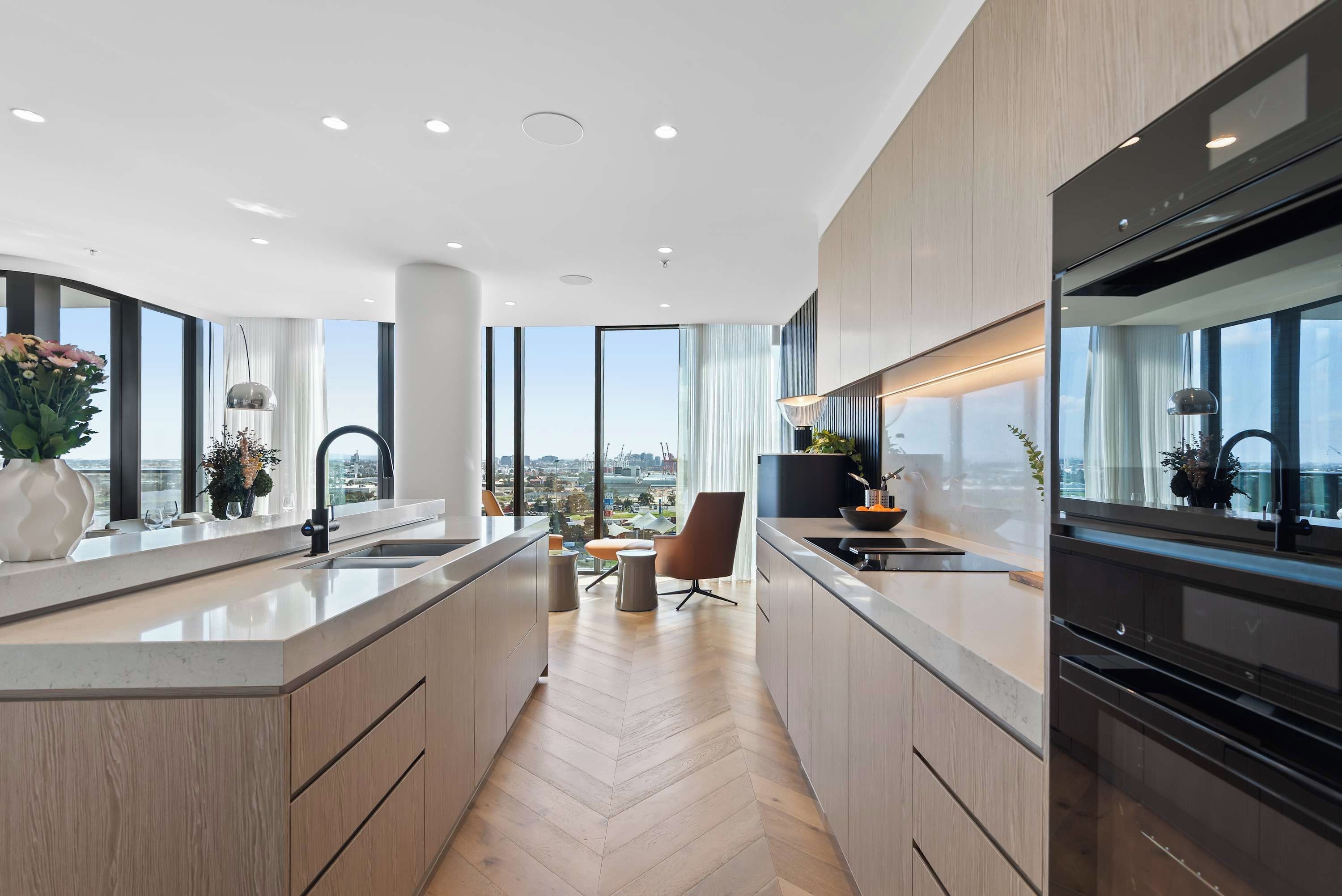 A modern kitchen with a large island, built-in appliances, and a view of the city.