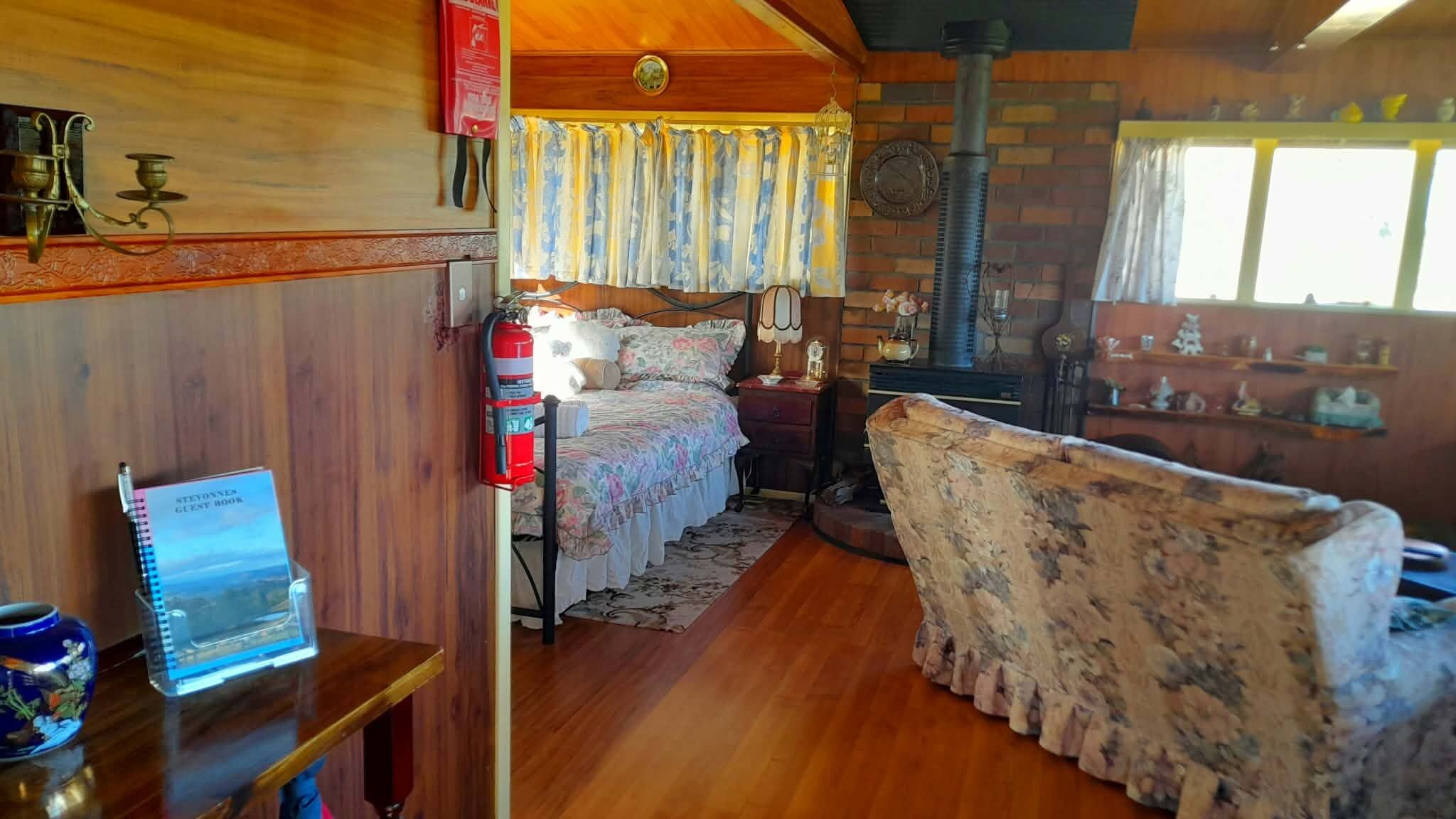 A cozy room with a bed, a fireplace, a wooden ceiling, and a small table with a laptop.
