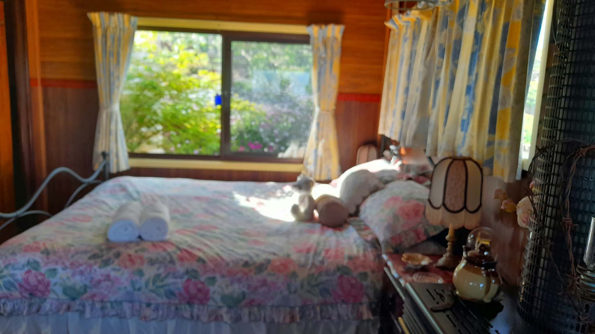 A bed with a floral bedspread, a bedside lamp, and a window with curtains.