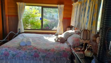 A bed with a floral bedspread, a bedside lamp, and a window with curtains.