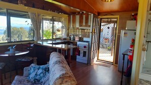 A cozy kitchen with a dining area, wooden cabinets, a stove, and a view through the window.
