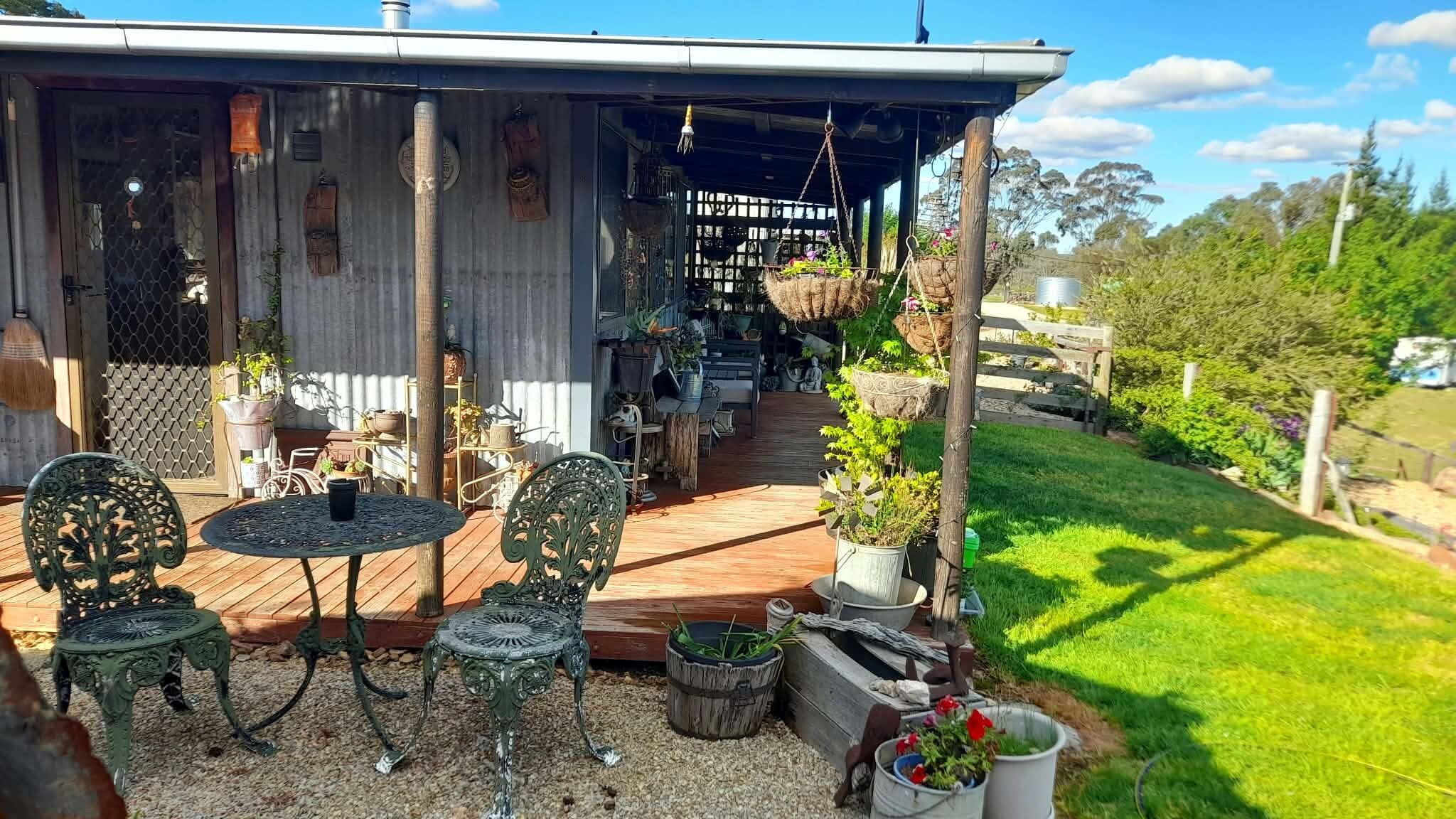 Eine Terrasse im Freien mit überdachter Sitzgruppe, umgeben von Blumentöpfen und einem Holzboden.
