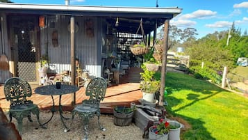 Eine Terrasse im Freien mit überdachter Sitzgruppe, umgeben von Blumentöpfen und einem Holzboden.
