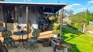 Eine Terrasse im Freien mit überdachter Sitzgruppe, umgeben von Blumentöpfen und einem Holzboden.
