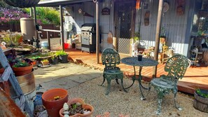 Eine Terrassenanlage mit Tisch und Stühlen, umgeben von Kübelpflanzen und einem Wasserspiel.