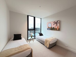 A modern bedroom with two beds, a large window, and a city view. - Jaw-dropping Views from Brand New 3bd Luxe Home (Melbourne)