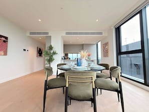 Un espace repas moderne avec une table ronde, six chaises et une plante en pot.