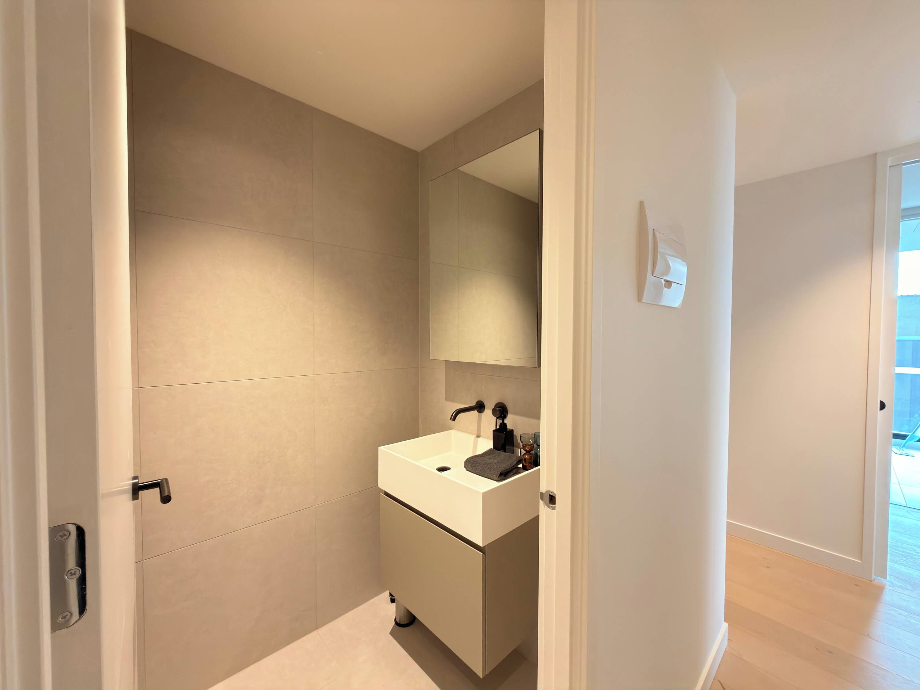 A modern bathroom with a white sink, a mirror, and a towel rack.