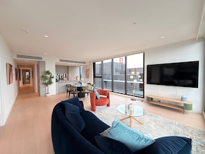A modern living room with a sofa, a coffee table, and a TV. - Jaw-dropping Views from Brand New 3bd Luxe Home (Melbourne)