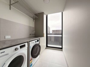 A compact laundry room with a washing machine, dryer, and a small sink. - Jaw-dropping Views from Brand New 3bd Luxe Home (Melbourne)