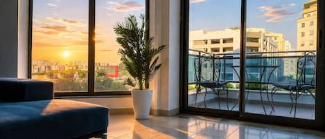 A modern living room with a large window, a sofa, a potted plant, and a balcony with a railing.