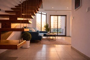 A modern living room with a staircase, a sofa, a coffee table, and a potted plant. - Loft italiano (Tunis)