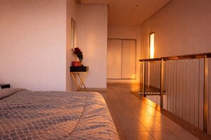 A hotel room with a bed, a nightstand with a vase of flowers, and a view of the hallway. - Loft italiano (Tunis)