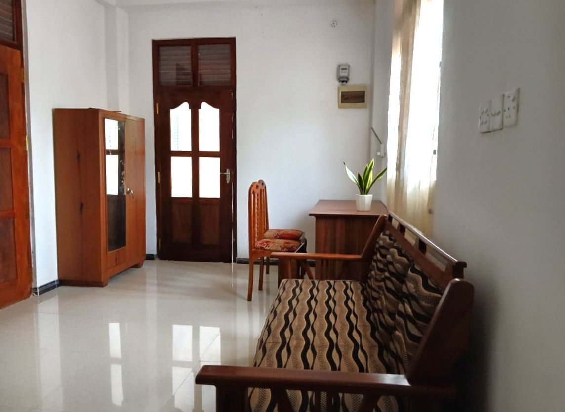 A room with a wooden sofa, a wooden chair, a small table, and a cabinet.
