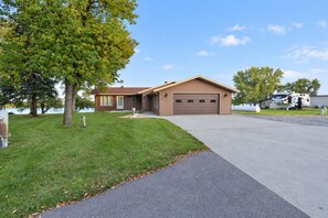 A single-story house with a garage, a paved driveway, and a grassy lawn.