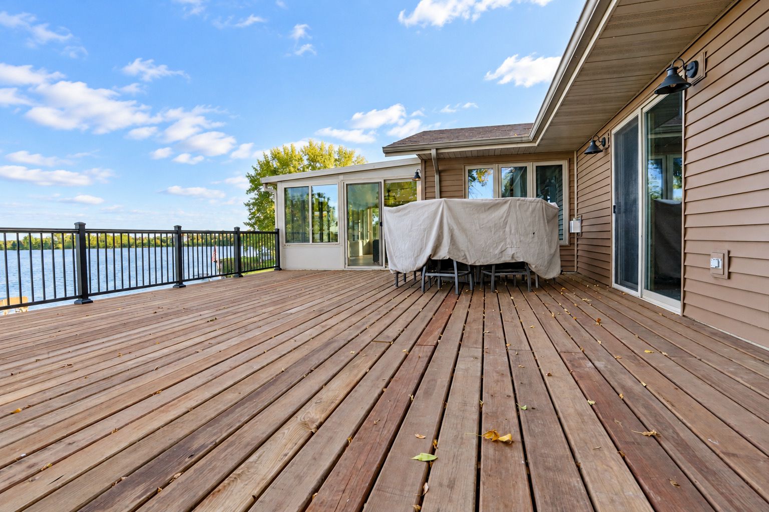 A wooden deck with a table and chairs, overlooking a body of water.
