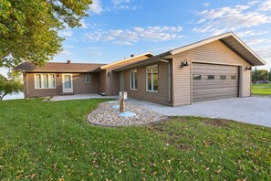 Une maison à deux étages avec un garage, un patio couvert et un jardin aménagé à l’avant.